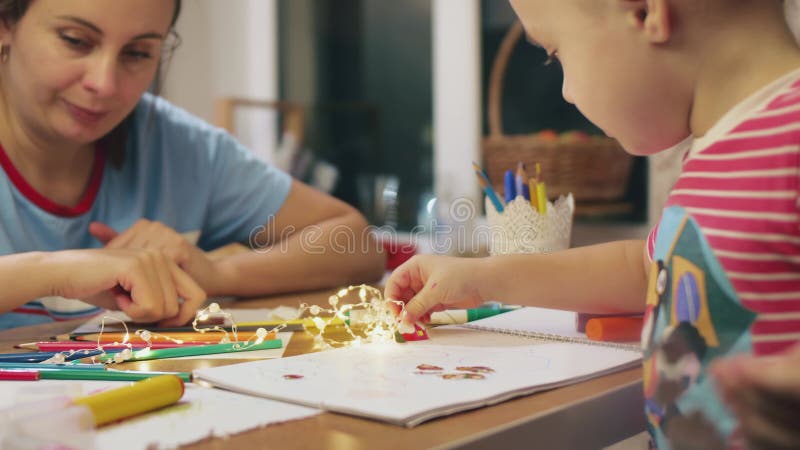 до новогодних праздников мать и сын дошкольного возраста проводят время вместе, рисуя санту клус и осторожно