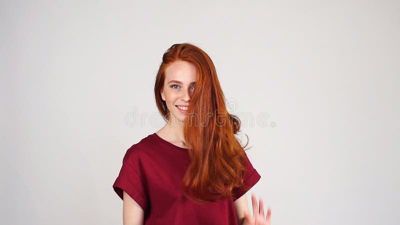 Довольно жизнерадостная девушка redhead смеется над на камере на белой предпосылке в замедленном движении