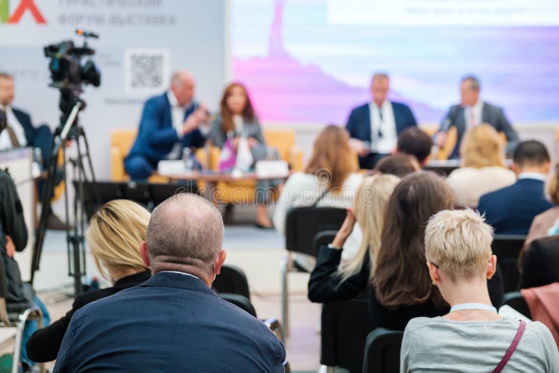 Group of unrecognizable speakers sitting on stage and discussing contemporary business technologies in auditorium with audience. Group of unrecognizable speakers sitting on stage and discussing contemporary business technologies in auditorium with audience