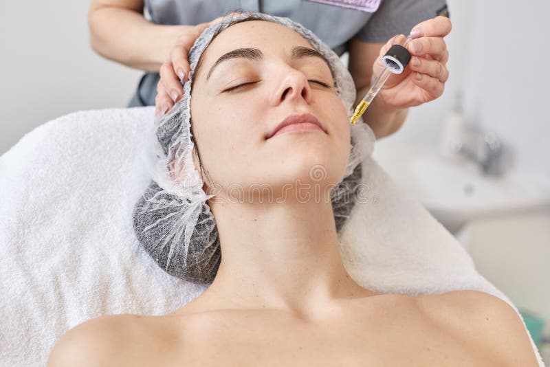 Доктор делает процедуру по beautician, сыворотку витамина applys для того чтобы смотреть на красивой женщины, клиента клиники кос стоковая фотография rf Доктор делает процедуру по beautician, сыворотку витамина applys для того чтобы смотреть на красивой женщины, клиента клиники кос стоковая фотография rf