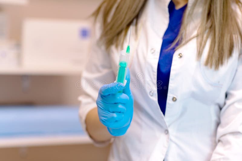 Доктор подготавливает дать впрыску Доктор, женская медсестра или anesthetist с хирургической иглой стоковое фото rf Доктор подготавливает дать впрыску Доктор, женская медсестра или anesthetist с хирургической иглой стоковое фото rf