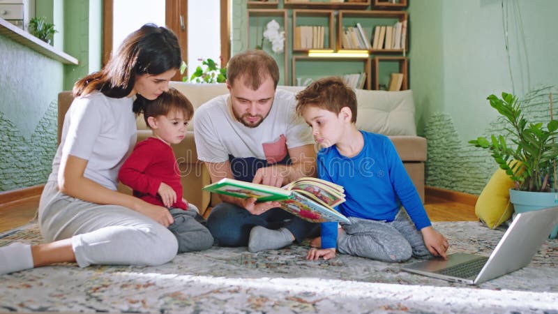 Дом отдыха в семье гостиной молодой все вместе на поле, который читает книгу истории, они очень счастливая расходы акции видеоматериалы