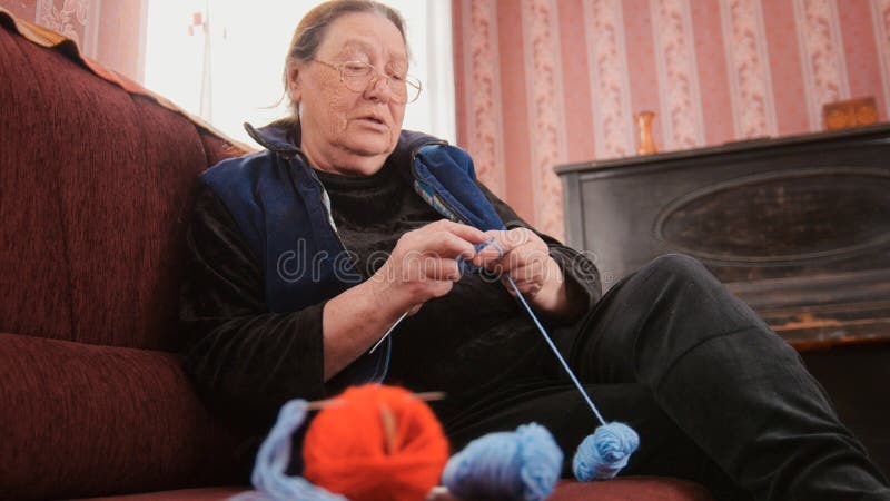 Дом пенсионера старухи - шерсть knits socks сидеть на софе - пожилое хобби дамы стоковые фото Дом пенсионера старухи - шерсть knits socks сидеть на софе - пожилое хобби дамы стоковые фото
