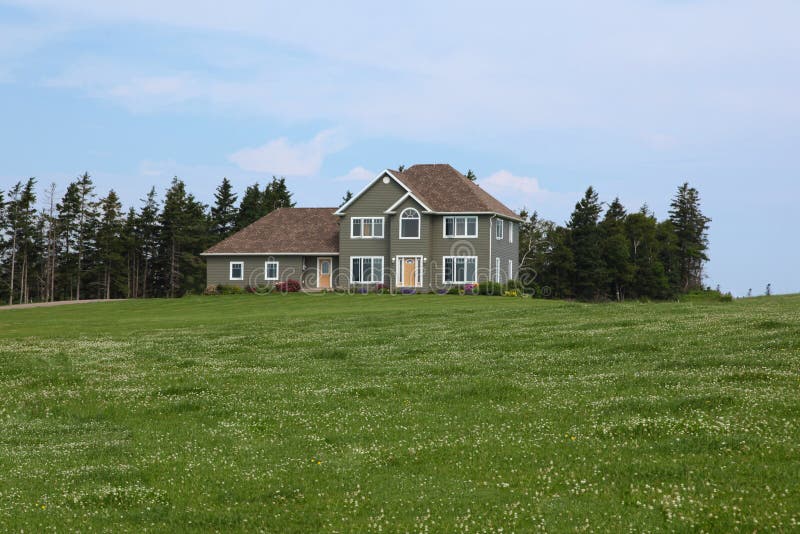 Scenic view of modern house in countryside with meadow or field in foreground. Scenic view of modern house in countryside with meadow or field in foreground.