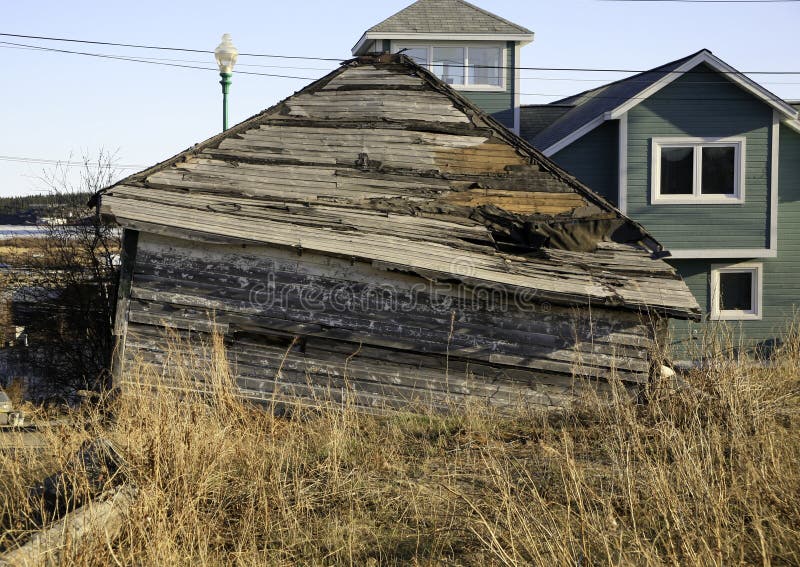 This old house has just about fallen over. in the background are new homes. This old house has just about fallen over. in the background are new homes.