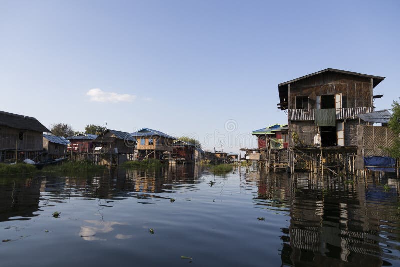 Дома ходулей деревянные отражая в деревне озера Inle, положении Шани, Мьянме стоковое фото rf Дома ходулей деревянные отражая в деревне озера Inle, положении Шани, Мьянме стоковое фото rf