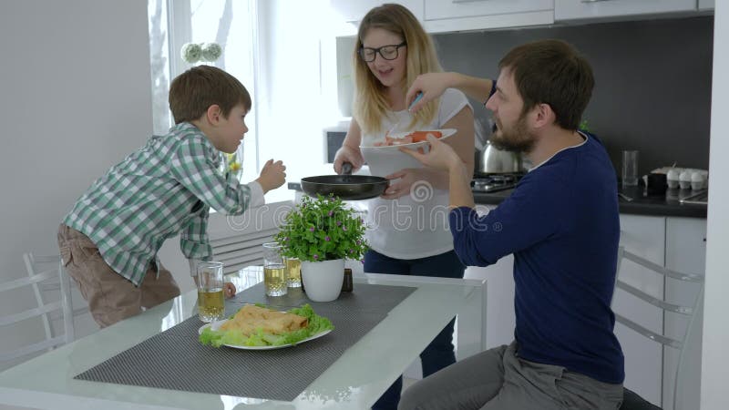 Домашние выходные, мама и папа при ребенок подготавливая еду для завтрака в кухне