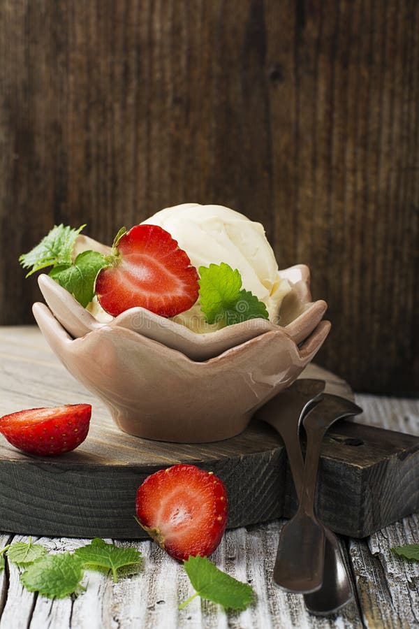 Домодельное cream мороженое от органической сливк коровы в винтажной керамической вазе с свежими клубниками и Мелиссой в деревенс стоковая фотография rf Домодельное cream мороженое от органической сливк коровы в винтажной керамической вазе с свежими клубниками и Мелиссой в деревенс стоковая фотография rf
