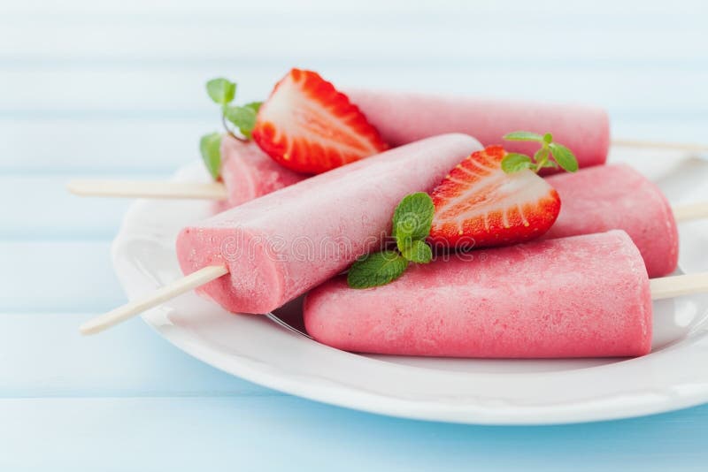 Домодельные мороженое или popsicles клубники в плите на голубом деревянном столе, который замерли фруктовом соке стоковая фотография