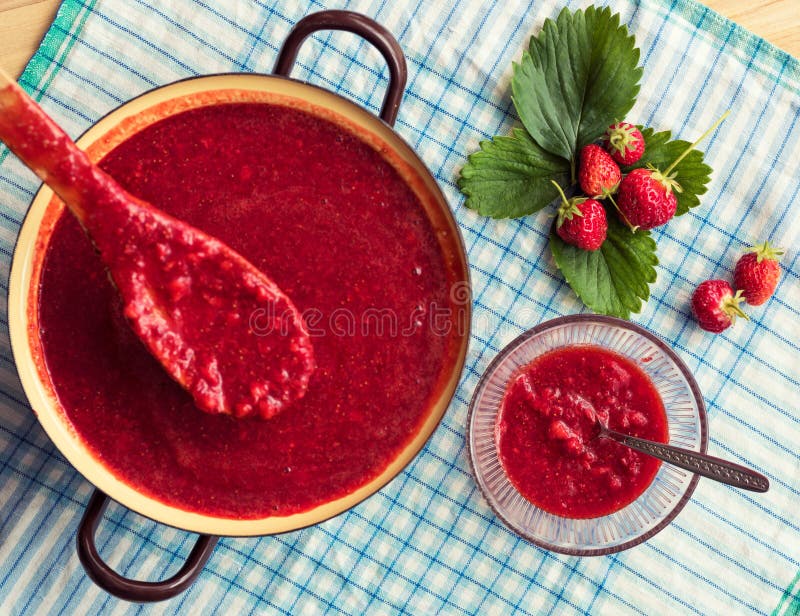 Домодельный варить варенья клубники (marmelade) Большой бак с горячим вареньем и свежими клубниками стоковое фото
