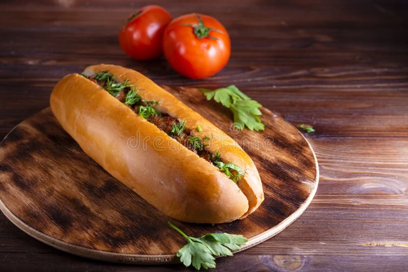 Домодельная горячая сосиска еды заполненная с мясом и овощами в деревянной плите на конце деревянного стола вверх