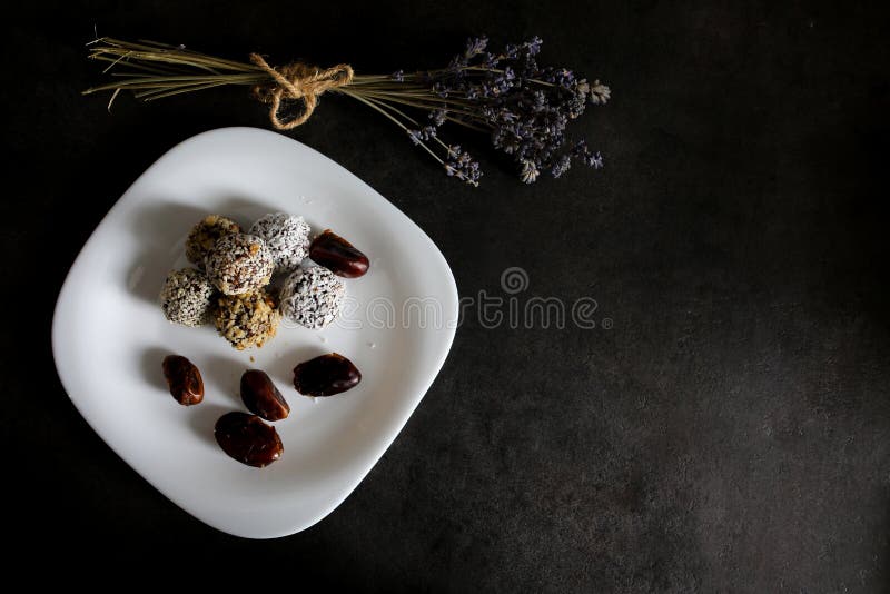 Домодельные сырцовые трюфеля с какао, гайками, кокосом и датами на белой плите и серой таблице Лаванда на предпосылке Vegan, орга стоковое фото Домодельные сырцовые трюфеля с какао, гайками, кокосом и датами на белой плите и серой таблице Лаванда на предпосылке Vegan, орга стоковое фото