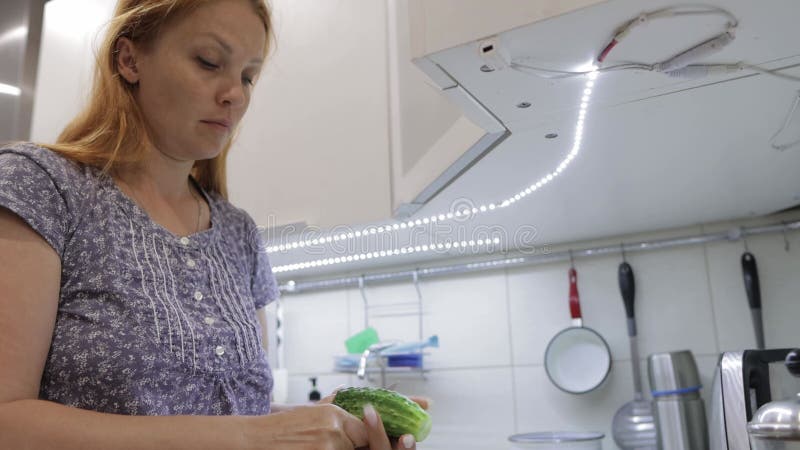 домохозяйка на кухне режет огурцы для овощного салата акции видеоматериалы