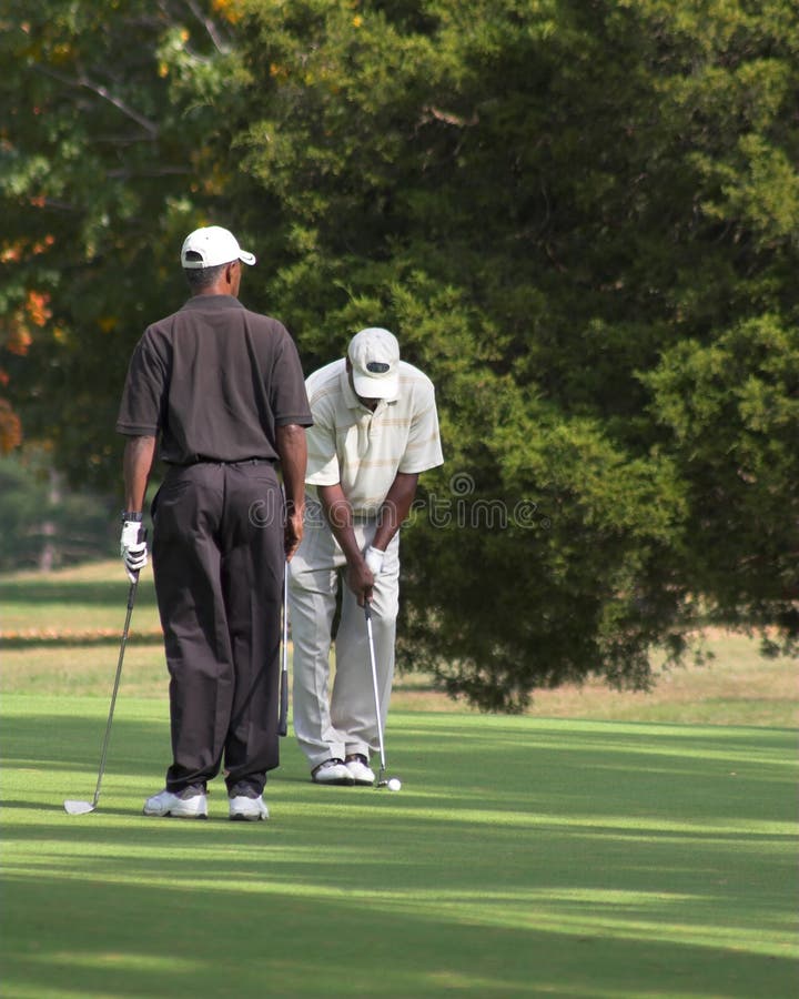 2 men enjoying a beautiful day playing a friendly game of golf. 2 men enjoying a beautiful day playing a friendly game of golf