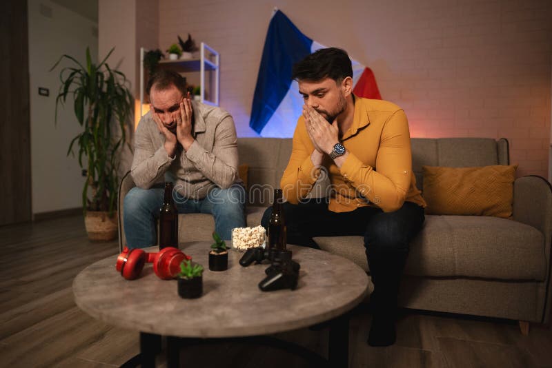 Друзья делятся напряженным моментом во время соревновательной игровой ночи дома в окружении закусок и напитков стоковое фото