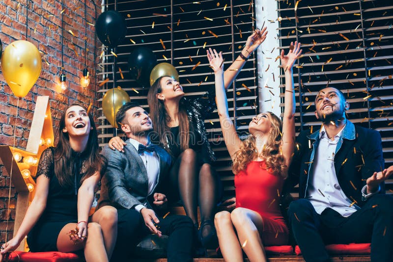 Друзья наслаждаясь партией и имея confetti потехи бросая стоковое фото rf Друзья наслаждаясь партией и имея confetti потехи бросая стоковое фото rf