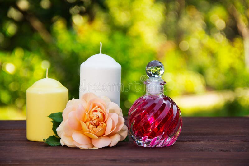 Душистое розовое масло в красивой стеклянной бутылке Розовые элексир, свечи и цветки Принципиальная схема спы Романтичная принцип