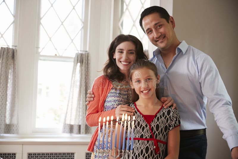 Еврейские родители и усмехаться дочери, освещенный свечи на menorah стоковые фотографии rf Еврейские родители и усмехаться дочери, освещенный свечи на menorah стоковые фотографии rf