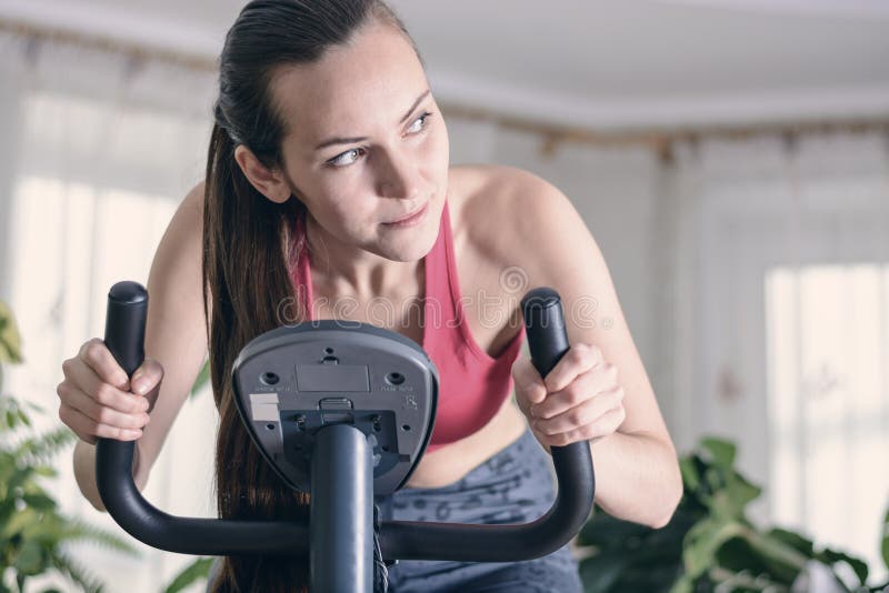 Европейская тренировка женщины cardio разрабатывает дома на велотренажере Концепция для потери веса Мотивированная и сфокусирован стоковая фотография rf Европейская тренировка женщины cardio разрабатывает дома на велотренажере Концепция для потери веса Мотивированная и сфокусирован стоковая фотография rf
