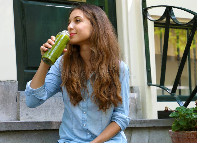Еда Vegan и концепция периода отдыха вытрезвителя Красивая девушка сидя вне ее дома выпивая зеленый сок Здоровая диета vegan вытр стоковое фото Еда Vegan и концепция периода отдыха вытрезвителя Красивая девушка сидя вне ее дома выпивая зеленый сок Здоровая диета vegan вытр стоковое фото