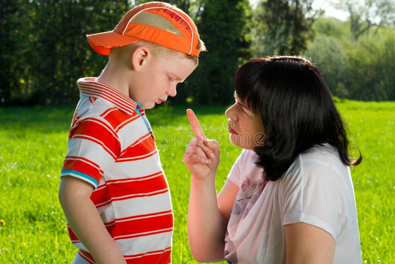 Mother scolding her son with pointed finger in park. Mother scolding her son with pointed finger in park