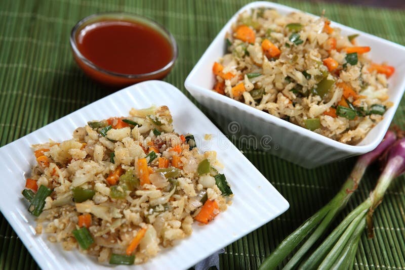 Cauliflower Fried Rice tastes delicious. It is quite easy to make at home. Fried rice is a dish of cooked rice that has been stir-fried in a frying pan and is usually mixed with other ingredients such as eggs, vegetables, seafood, or meat. The ingredients for Cauliflower Fried Rice are cauliflower, onion, peas, carrots, oil, ginger, green capsicum, tomato sauce, ghee, salt. Serve this as a tasty low-carb side dish, or as a meal in itself. Cauliflower Fried Rice packs in a serious load of vegetables, and very small amount of carbs. normal fried rice as a meal, Cauliflower Fried Rice IS a healthy, satisfying complete meal in itself! Ingredients 1.5 tbsp oil , separated (vegetable, canola, peanut) 3 garlic cloves , minced 1 2 onion , finely chopped. 75g 2.5 oz ham or bacon , diced. 1 1 2 cups frozen diced peas, carrots, corn (mix, or other diced fresh veg of choice).400g (4 cups) cauliflower rice, raw (Note 1). 2 eggs , lightly whisked. 2 green onions , finely sliced.5 tbsp oil , separated (vegetable, canola, peanut). 3 garlic cloves , minced. 1 2 onion , finely chopped. 75g 2.5 oz ham or bacon , diced.1 1 2 cups frozen diced peas, carrots, corn (mix, or other diced fresh veg of choice). 400g (4 cups) cauliflower rice, raw (Note 1).2 eggs , lightly whisked. 2 green onions , finely sliced.Sauce - Mix .1 tbsp Mirin (or Chinese Cooking Wine) (sub dry sherry or cooking sake) (Note 2). 1 tbsp Oyster Sauce (sub Hoisin). 1.5 tbsp soy sauce , light or all purpose (Note 3). 1 tsp sesame oil , toastedInstructions Heat 1 tbsp oil in a large skillet over high heat. Add garlic and onion, cook for 30 seconds. Add ham, cook for 1 minute to release flavour. Add frozen vegetables, cook 2 minutes until carrot is almost cooked. Add cauliflower and Sauce. Cook, stirring regularly, for 4 minutes until sauce is reduced and cauliflower is almost cooked - firm, tender crisp, not soft and mushy. Push the cauliflower to one side of the skillet. Add 1 2 tbsp oil, let it heat up briefly, then pour in egg. Leave for 10 seconds, then leisurely scramble it. Once almost cooked, mix egg through cauliflower. Toss through green onions then serve immediately!. Cauliflower Fried Rice tastes delicious. It is quite easy to make at home. Fried rice is a dish of cooked rice that has been stir-fried in a frying pan and is usually mixed with other ingredients such as eggs, vegetables, seafood, or meat. The ingredients for Cauliflower Fried Rice are cauliflower, onion, peas, carrots, oil, ginger, green capsicum, tomato sauce, ghee, salt. Serve this as a tasty low-carb side dish, or as a meal in itself. Cauliflower Fried Rice packs in a serious load of vegetables, and very small amount of carbs. normal fried rice as a meal, Cauliflower Fried Rice IS a healthy, satisfying complete meal in itself! Ingredients 1.5 tbsp oil , separated (vegetable, canola, peanut) 3 garlic cloves , minced 1 2 onion , finely chopped. 75g 2.5 oz ham or bacon , diced. 1 1 2 cups frozen diced peas, carrots, corn (mix, or other diced fresh veg of choice).400g (4 cups) cauliflower rice, raw (Note 1). 2 eggs , lightly whisked. 2 green onions , finely sliced.5 tbsp oil , separated (vegetable, canola, peanut). 3 garlic cloves , minced. 1 2 onion , finely chopped. 75g 2.5 oz ham or bacon , diced.1 1 2 cups frozen diced peas, carrots, corn (mix, or other diced fresh veg of choice). 400g (4 cups) cauliflower rice, raw (Note 1).2 eggs , lightly whisked. 2 green onions , finely sliced.Sauce - Mix .1 tbsp Mirin (or Chinese Cooking Wine) (sub dry sherry or cooking sake) (Note 2). 1 tbsp Oyster Sauce (sub Hoisin). 1.5 tbsp soy sauce , light or all purpose (Note 3). 1 tsp sesame oil , toastedInstructions Heat 1 tbsp oil in a large skillet over high heat. Add garlic and onion, cook for 30 seconds. Add ham, cook for 1 minute to release flavour. Add frozen vegetables, cook 2 minutes until carrot is almost cooked. Add cauliflower and Sauce. Cook, stirring regularly, for 4 minutes until sauce is reduced and cauliflower is almost cooked - firm, tender crisp, not soft and mushy. Push the cauliflower to one side of the skillet. Add 1 2 tbsp oil, let it heat up briefly, then pour in egg. Leave for 10 seconds, then leisurely scramble it. Once almost cooked, mix egg through cauliflower. Toss through green onions then serve immediately!