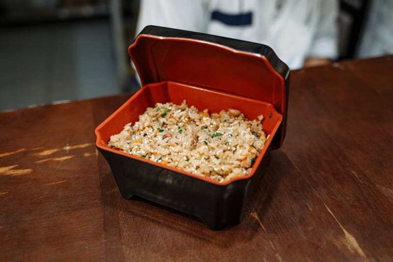 Жареные рисы с овощами в черной прямоугольной коробке с красной кишкой на предпосылке деревянного стола стоковое фото Жареные рисы с овощами в черной прямоугольной коробке с красной кишкой на предпосылке деревянного стола стоковое фото