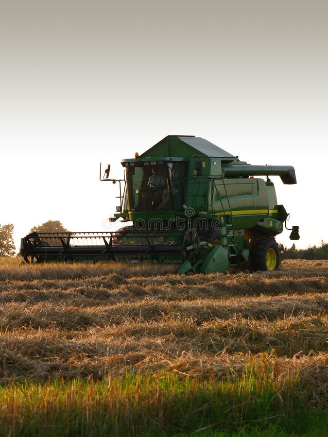A green and yellow combine harvester in action on a field. A green and yellow combine harvester in action on a field