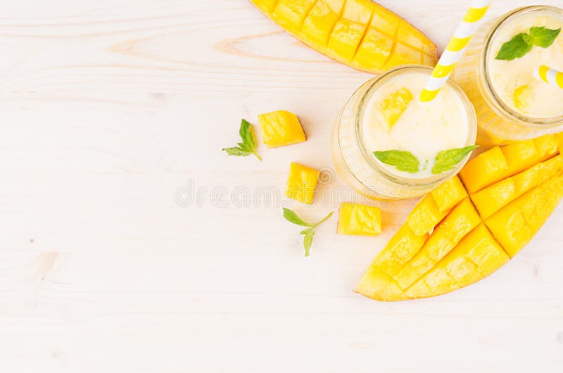 Желтый smoothie плодоовощ манго в стекле раздражает с соломой, листьями мяты, кусками манго, взгляд сверху Белая предпосылка дере стоковое изображение rf Желтый smoothie плодоовощ манго в стекле раздражает с соломой, листьями мяты, кусками манго, взгляд сверху Белая предпосылка дере стоковое изображение rf