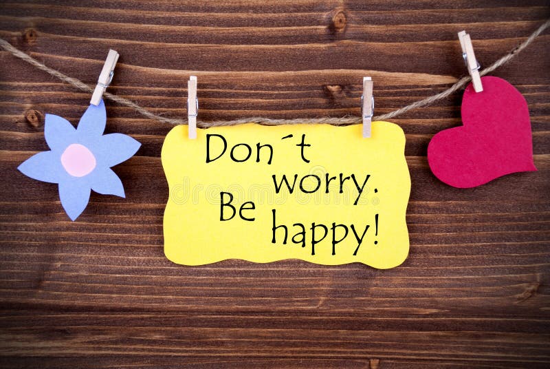 Yellow Label Don't Worry Be Happy On Wooden Background With Two Symbols Like Heart And Flower. Yellow Label Don't Worry Be Happy On Wooden Background With Two Symbols Like Heart And Flower