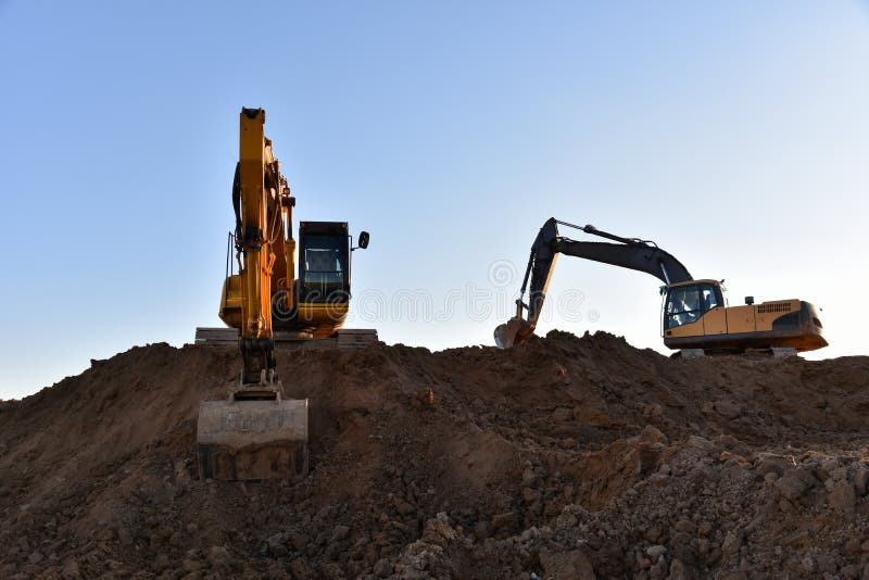 Желтые экскаваторы во время earthmoving на открытом карьере на фоне голубого неба.. Строительная техника и earthmoving тяжелое обо стоковая фотография