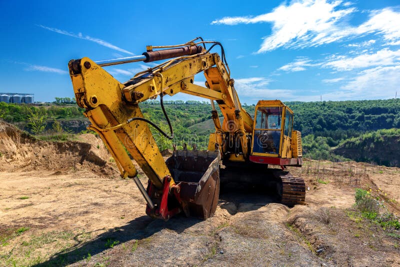 Желтый экскаватор во время earthmoving на открытом карьере на фоне голубого неба.. Строительная техника и earthmoving тяжелое обор стоковые изображения rf