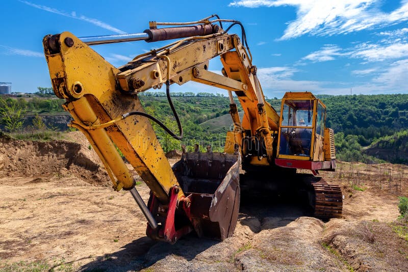 Желтый экскаватор во время earthmoving на открытом карьере на фоне голубого неба.. Строительная техника и earthmoving тяжелое обор стоковое фото