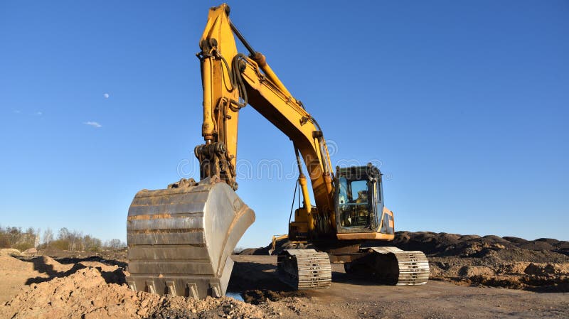 Желтый экскаватор во время earthmoving на открытом карьере на фоне голубого неба.. Строительная техника и earthmoving тяжелое обор стоковое фото