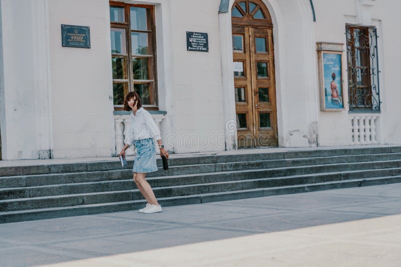 женская лестница. бизнес-леди в белой рубашке и джинсовой юбке идет по ступенькам старинного здания стоковое изображение