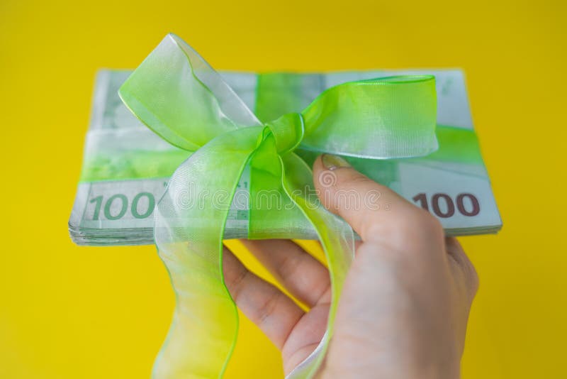 Женская рука держа пакет 100 банкнот евро с зелеными смычк-узлом, подарком или дивидендами концепцией, деньгами Европейского союз стоковое фото Женская рука держа пакет 100 банкнот евро с зелеными смычк-узлом, подарком или дивидендами концепцией, деньгами Европейского союз стоковое фото