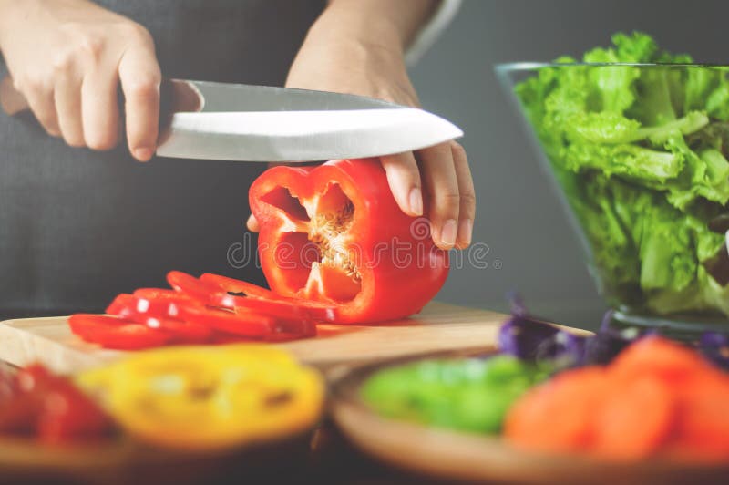 Женские болгарские перцы красного цвета вырезывания Варить еду vegan здоровое острословие стоковая фотография rf Женские болгарские перцы красного цвета вырезывания Варить еду vegan здоровое острословие стоковая фотография rf