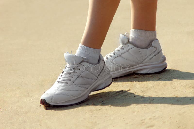 Woman in sneakers standing on sand beach or tennis-court conceptual. Woman in sneakers standing on sand beach or tennis-court conceptual