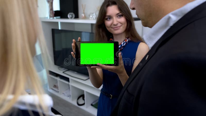 Женский маклер показывая зеленую таблетку экрана с app для умного управления дома стоковая фотография Женский маклер показывая зеленую таблетку экрана с app для умного управления дома стоковая фотография