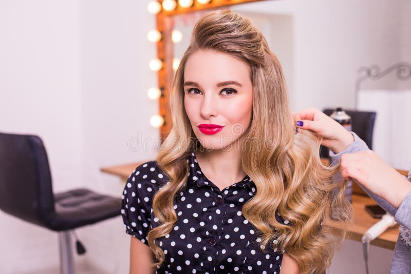 Женский парикмахер стоя и делая стиль причёсок к милой симпатичной ...