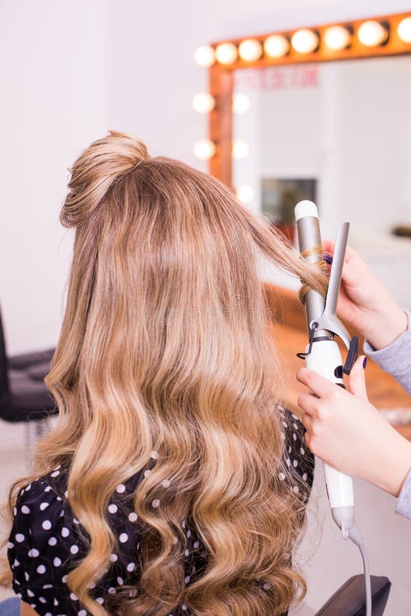 Женский парикмахер стоя и делая стиль причёсок к милой симпатичной ...