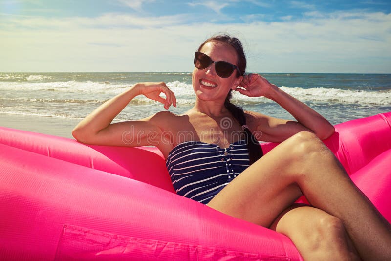 Женский усмехаться в ее коричневых солнечных очках на румяном airbed на t стоковая фотография
