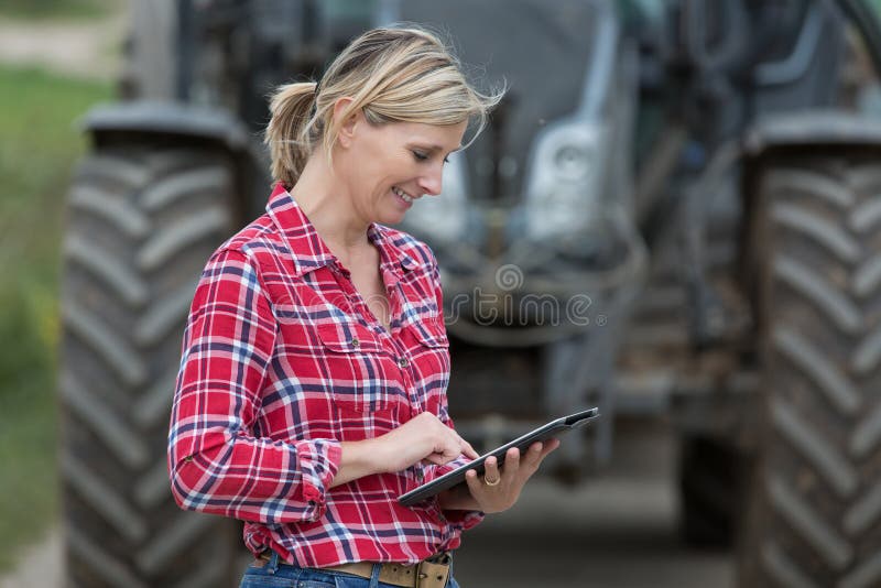 Female farmer calling technician and using tablet. Female farmer calling technician and using tablet