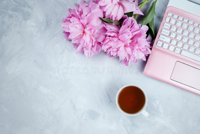 Женственный модель-макет дела с розовыми компьтер-книжкой, букетом пионов и чашкой теплого чая стоковые изображения rf Женственный модель-макет дела с розовыми компьтер-книжкой, букетом пионов и чашкой теплого чая стоковые изображения rf