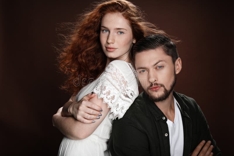 Женщина Redhead и бородатый человек стоя спина к спине пока представляющ для съемки студии стоковое фото Женщина Redhead и бородатый человек стоя спина к спине пока представляющ для съемки студии стоковое фото