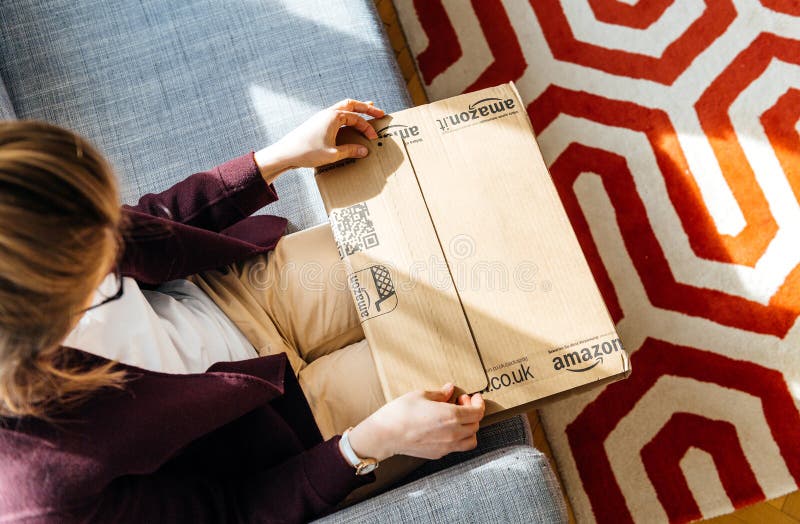 Женщина unboxing распаковывающ Амазонку com кладет в коробку стоковое фото rf Женщина unboxing распаковывающ Амазонку com кладет в коробку стоковое фото rf