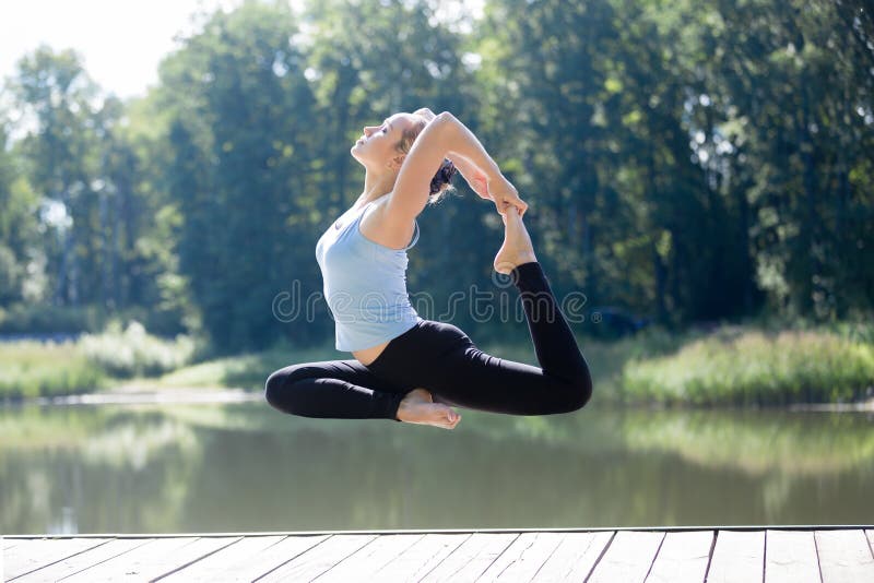 Женщина Yogi делая королевское представление голубя в средний воздух стоковые фотографии rf Женщина Yogi делая королевское представление голубя в средний воздух стоковые фотографии rf