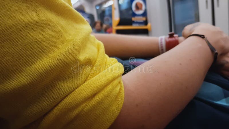 Женщина в желтой блузке сидя в поезде города, идя домой, городской образ жизни