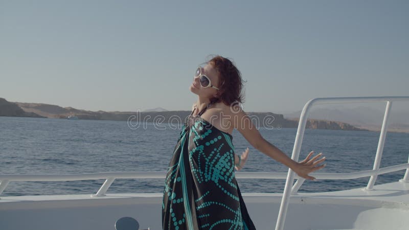 женщина в одежде наслаждается видом на море на яхте. счастливая расслабленная женщина, стоящая на лодке, смотрящая на камеру. морс видеоматериал