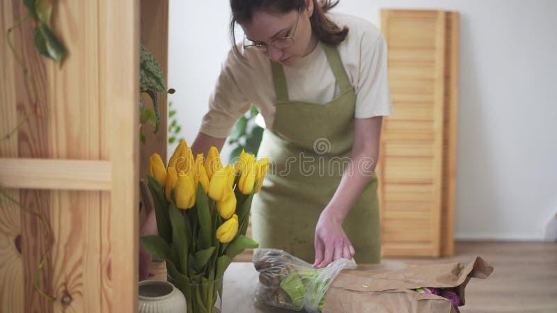 Женщина-декоратор распаковывает свежие цветы. украшение праздника цветами. деловая женщина на работе